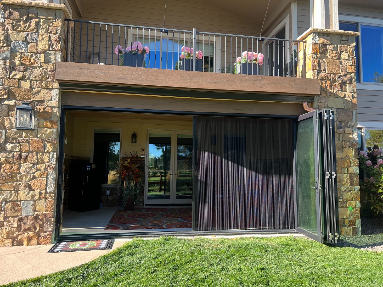 Black Win-Dor folding patio door folded open with the Genius pleated screen partly closed