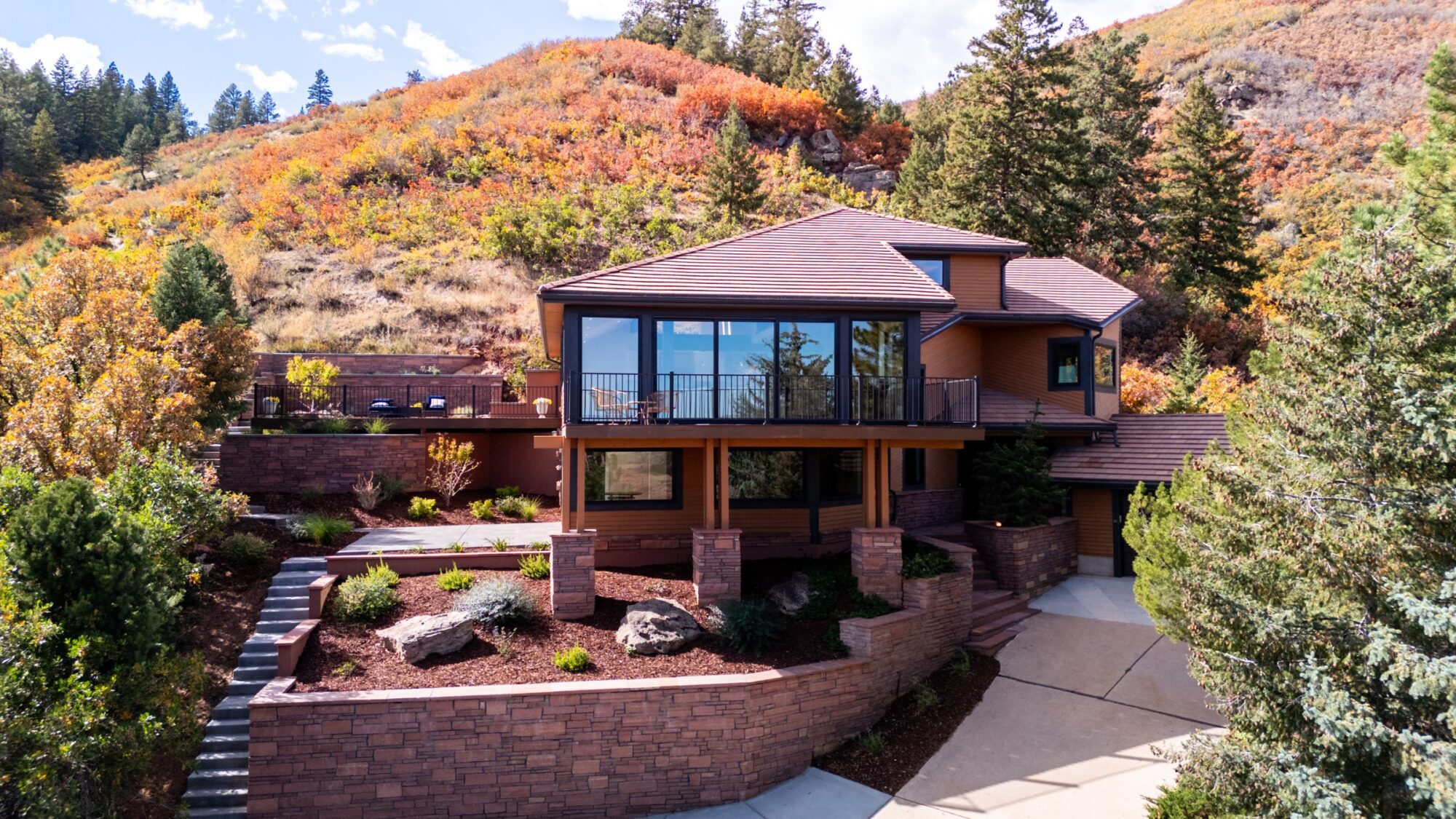Hillside home in fall with Jet Black Win-Dor 1750 Series windows and a 3750 Series sliding patio door, exterior.